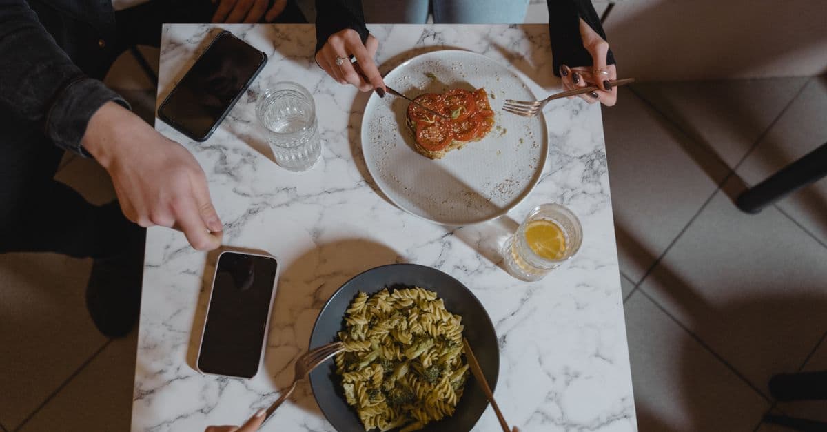 Overhead view of pasta and bruschetta on a marble table with two diners