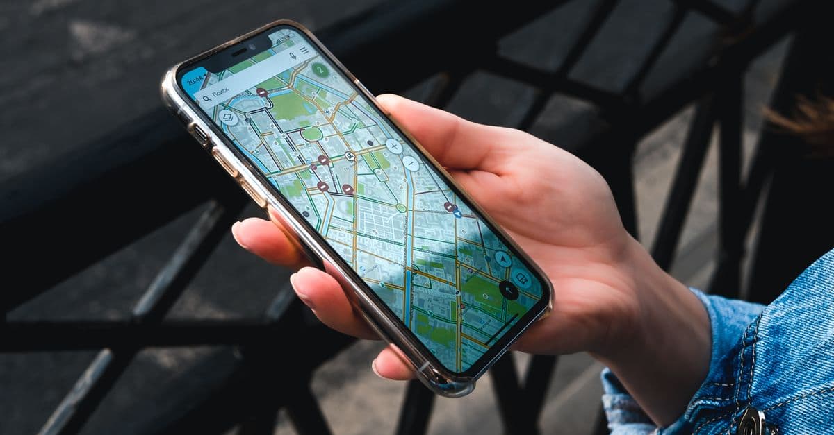 A person holding a smartphone showing a map with location pins on a city street