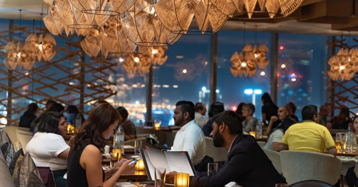 A busy restaurant dining room at night with diners seated at tables