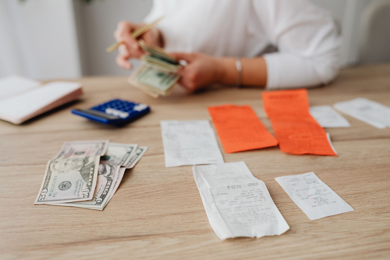 A person using a calculator and cash to work through a budget