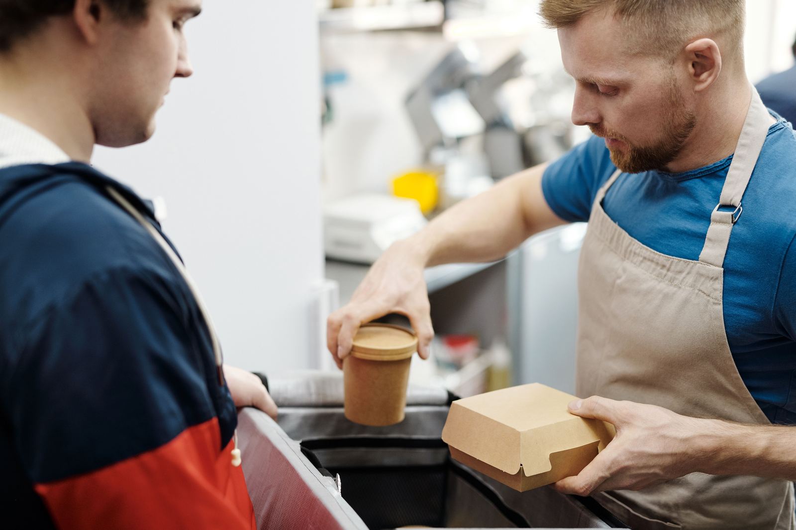 A server handing a takeout order to a customer across the counter