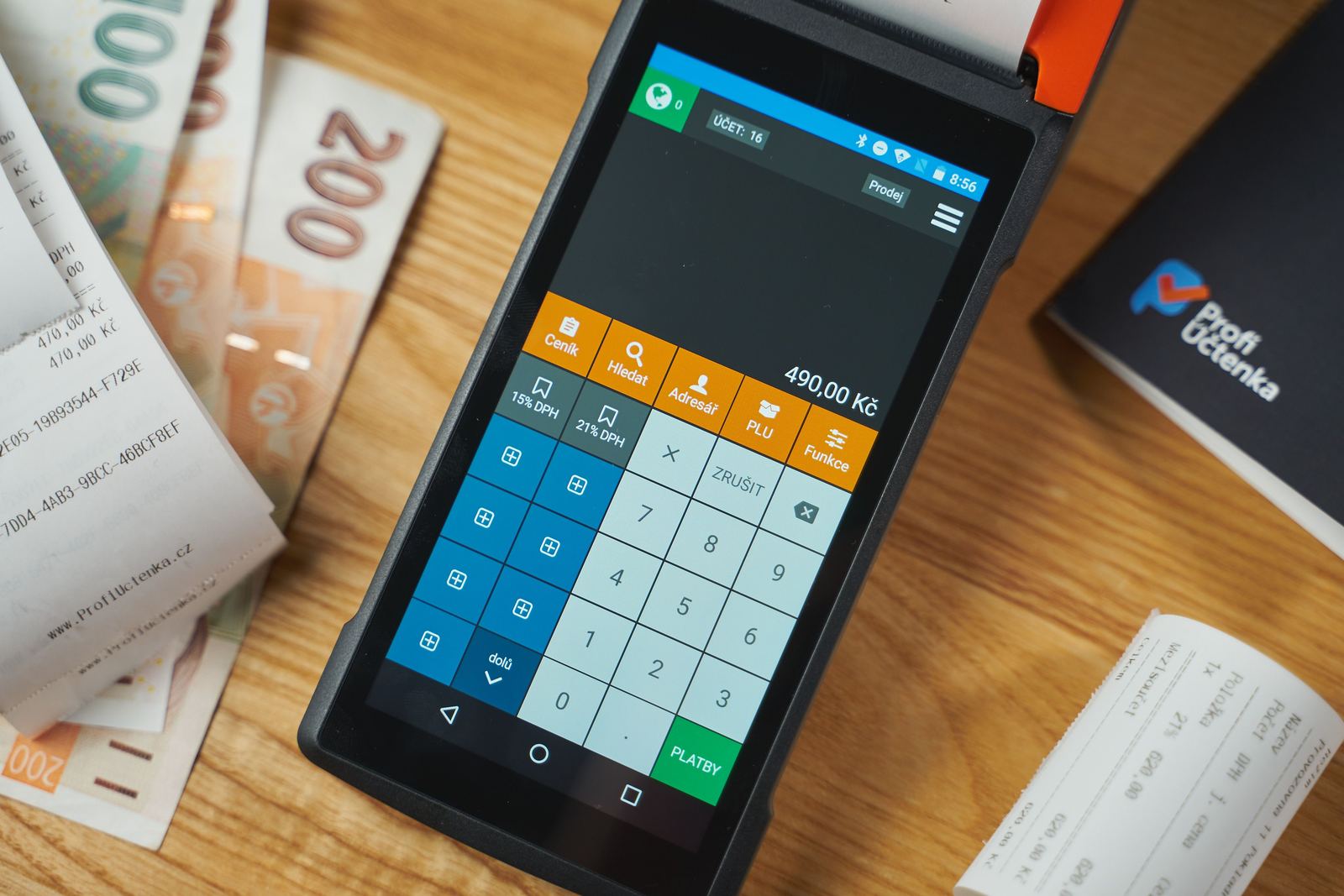 A digital payment terminal on a desk with receipts and cash