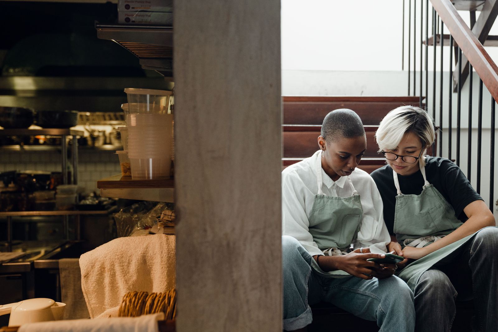 Restaurant staff on a break near the kitchen, checking a phone