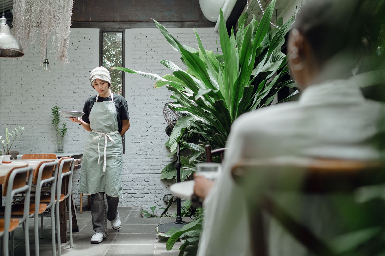 A server carrying a plate to a guest in a bright restaurant