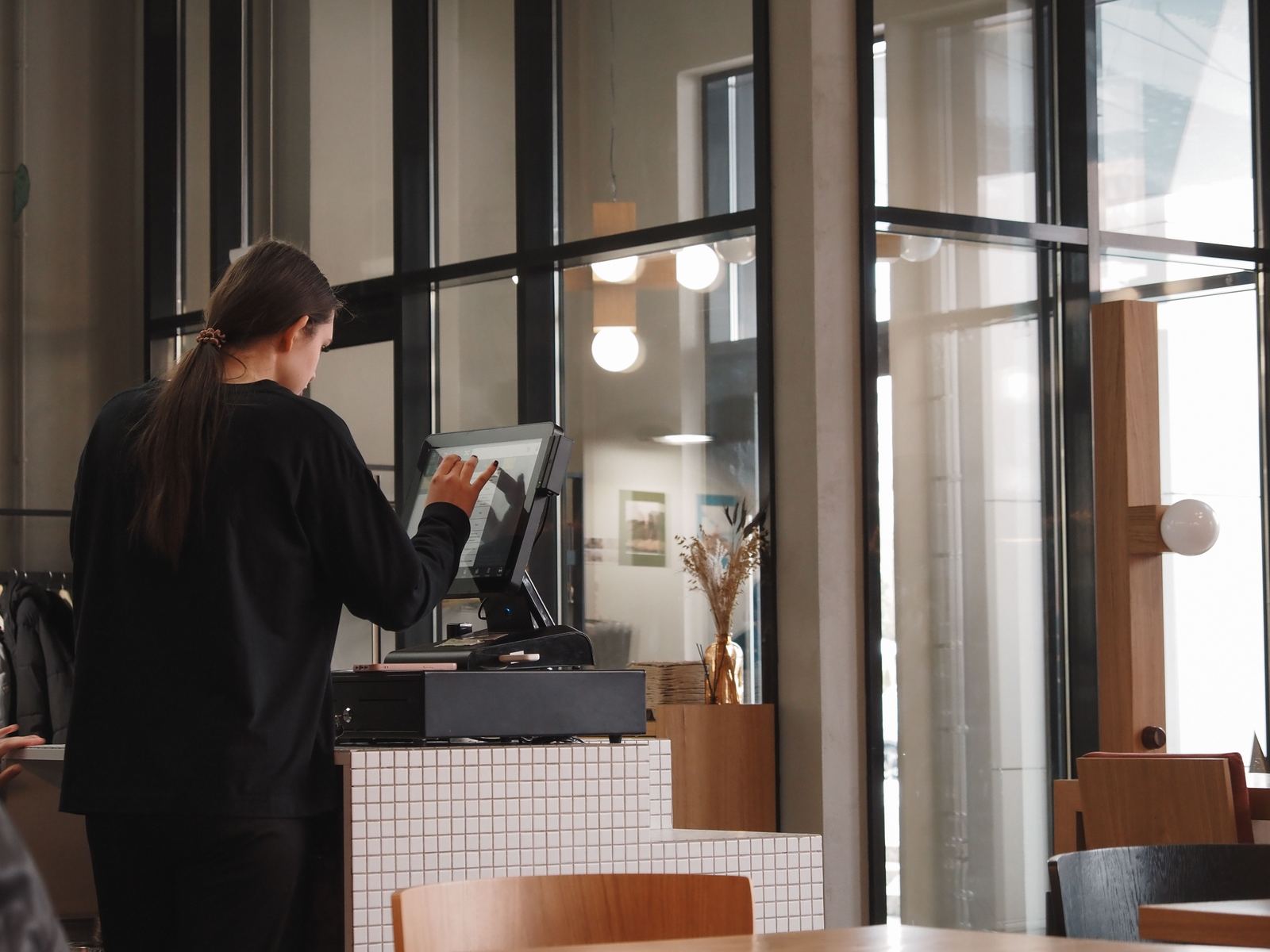 A café employee entering an order on a touchscreen register
